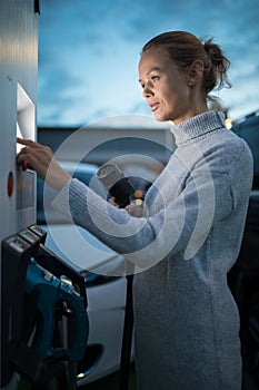 Young woman charging an electric vehicle