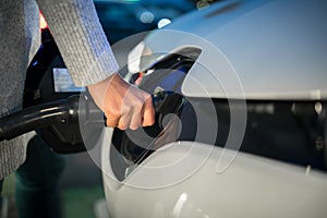 Young woman charging an electric vehicle