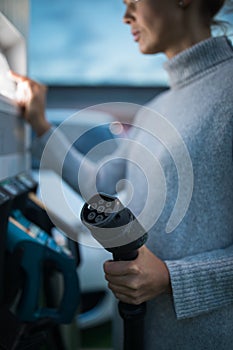 Young woman charging an electric vehicle