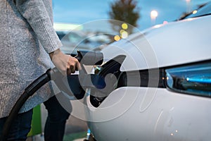 Young woman charging an electric vehicle photo