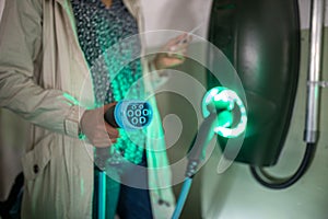 Young woman charging an electric vehicle in an underground garage