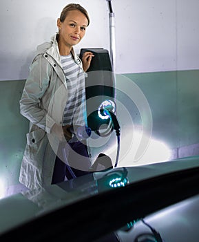 Young woman charging an electric vehicle photo