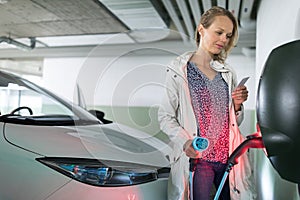 Young woman charging an electric vehicle photo