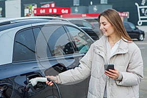 Giovane donna ricarica suo elettrico auto sul ricarica stazione la città 