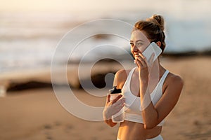 Young woman chatting on phone, post-yoga, beach sunset