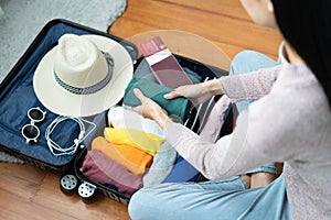 Young woman checking accessories and stuff in luggage on the bed at home before travel