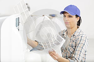 young woman checking and cleaning air conditioning system at home