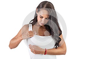 Young woman checking her breasts. Wearing a white top and doing self-exam to avoid cancer. Isolated background