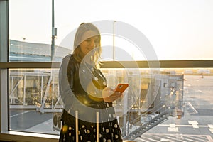 A young woman, checking her mobile phone, is prepared for boarding.