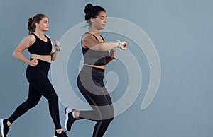 Young woman checking her smartwatches while running outdoors with a fitness buddy