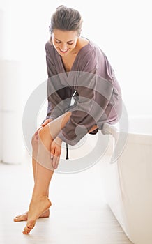 Young woman checking leg skin softness in bathroom