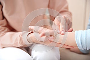 Young woman checking little girl`s pulse with fingers, closeup