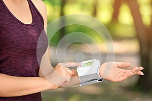 Young woman checking pulse outdoors