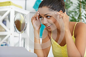 young woman checking skin in mirror