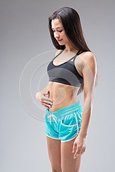 Young woman checks toned belly, defies societal pressures