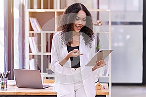 A young woman cheerful smiling standing and holding digital tablet In the office room