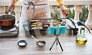 Young woman chef cooking outdoor while streaming online for webinar masterclass lesson at home during isolation quarantine - Food photo