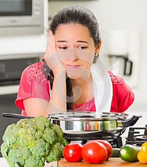 Young woman chef cooking with skeptical facial expressions, interacting frustrated body language