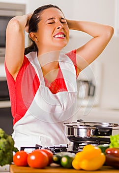 Young woman chef holding hair in frustration, discouraged facial expression, table with kettle and vegetables
