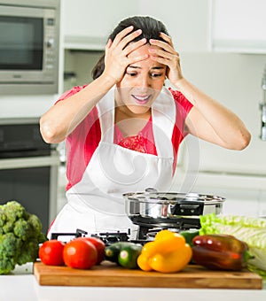 Young woman chef holding hair in frustration, discouraged facial expression, table with kettle and vegetables