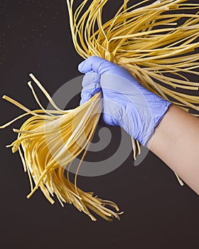 Young woman chef holds homemade pasta in the air over black background. Creative idea. Italian cuisine concept