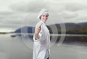 Young woman chef making horn gesture. Impolite