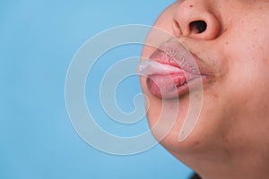 Young woman chewing gum and blowing bubble gum on blue background