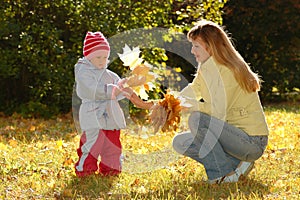 Young woman and child collect autumn sheets