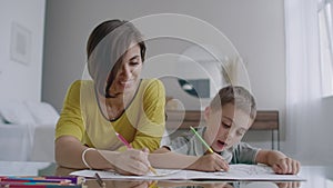 Young woman and child drawing together making picture with pencils in flat.