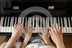 Young woman with child playing piano. Music lesson