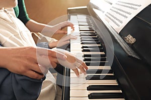 Young woman with child playing piano. Music lesson