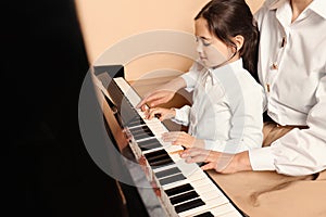 Young woman with child playing piano. Music lesson