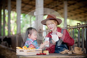 Young woman and children drinking fresh milk in a dairy farm