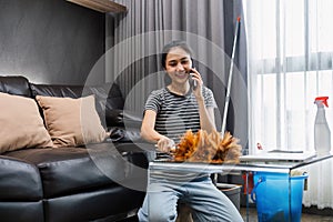 Young woman chit chat with friend on mobile while cleaning house on weekend