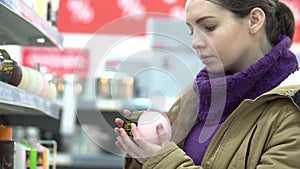 Young woman chooses candles in a supermarket