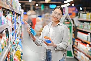 A young woman chooses household chemicals in a supermarket. Means for washing and cleaning the house