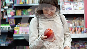 Young woman chooses ripe red tomatoes buying fresh vegetables in a supermarket