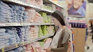 Young woman chooses towels in the supermarket
