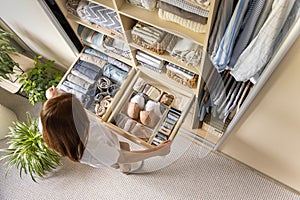 A young woman chooses which bra to wear while standing in front of a neatly arranged wardrobe. The concept of underwear