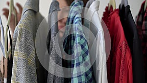 Young woman choosing clothes on a rack searching what to wear. Store or wardrobe