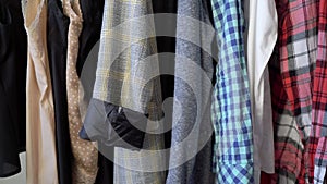 Young woman choosing clothes on a rack searching what to wear. Store or wardrobe