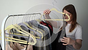 Young woman choosing clothes on a rack searching what to wear. Store or wardrobe