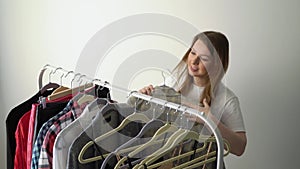 Young woman choosing clothes on a rack searching what to wear. Store or wardrobe