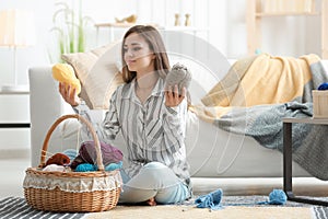 Young woman choosing color of knitting threads at home