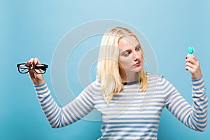 Young woman choosing between contact lenses or glasses
