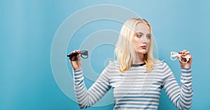 Young woman choosing between contact lenses or glasses