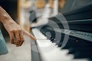 Young woman choosing digital piano in music store