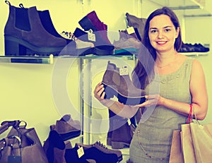 Young woman choosing fall boots in shoes store