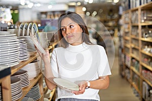 Young woman choosing new dishware at store