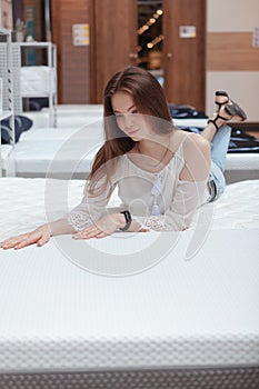 Young woman choosing new orthopedic bed